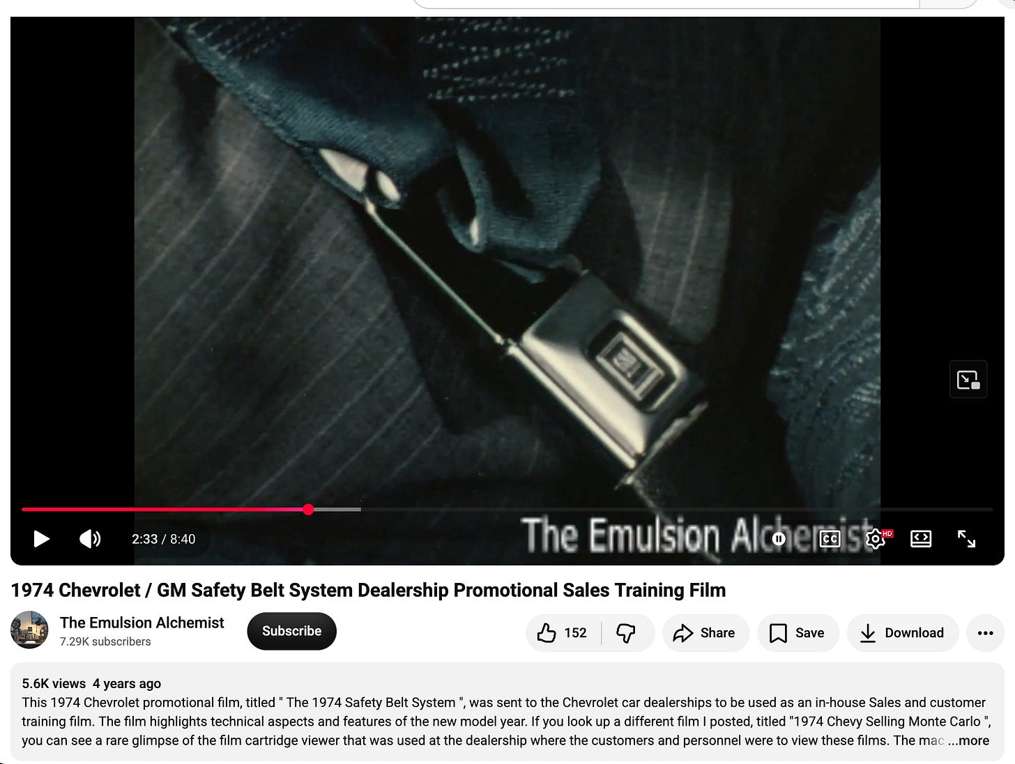 A still from a 1974 GM dealership training film showing a driver buckling a seat belt in a Chevrolet. A still from a 1974 GM dealership training film showing a driver buckling a seat belt in a Chevrolet.